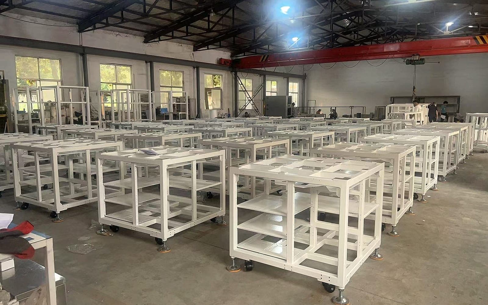 Rows of white metal frames on caster wheels in a workshop