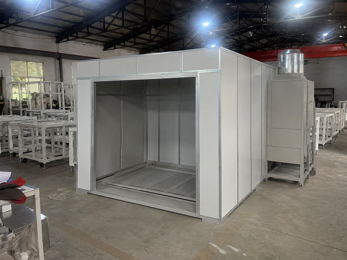 Illustrative configuration of a modular powder-coating booth structure under assembly in a factory